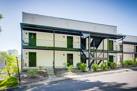 A white building with green doors and a staircase.